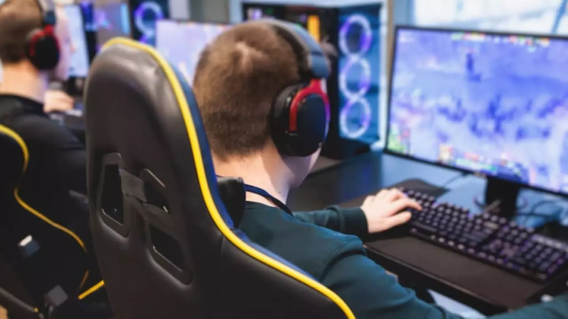 2 jonge e-sports die achter een scherm en toetsenbord zitten en gamen.